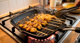 Brochetas de pollo Satay asándose en sartén grill con marcas doradas